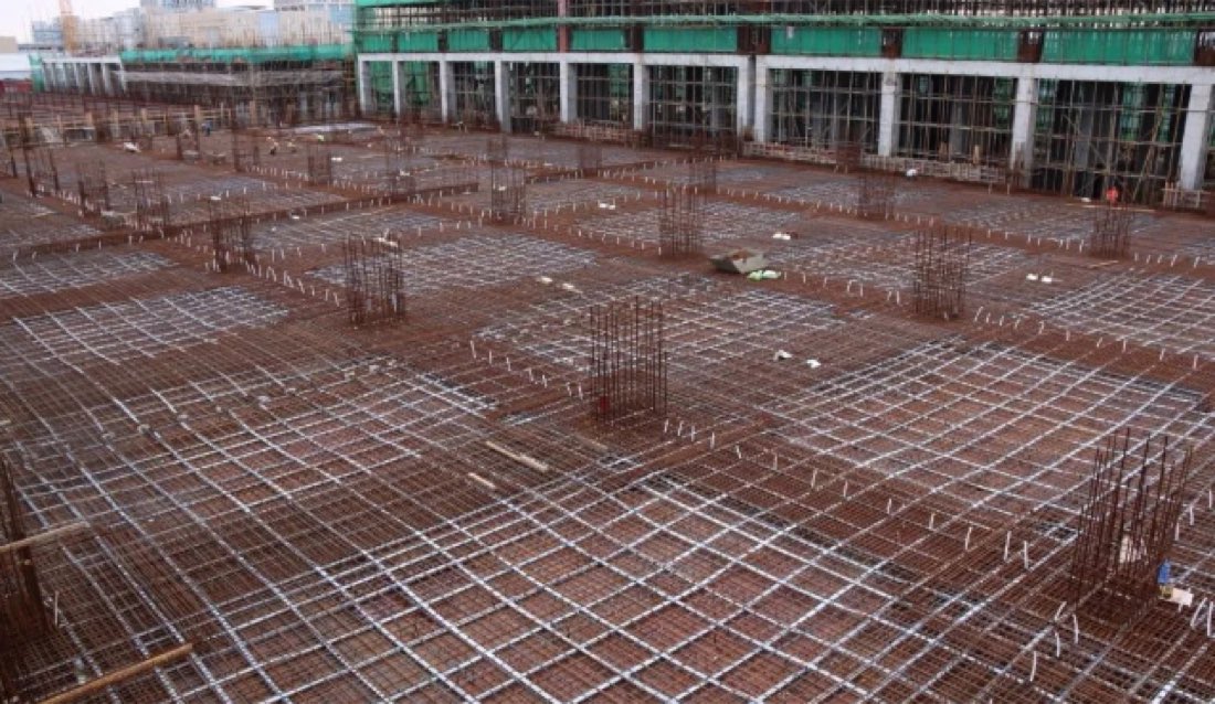 Site photograph showing prestressing installation coordinated with dense slab reinforcement before concrete placement.